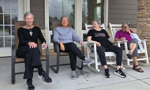 Four women residents sit in chairs on the patio at a ComfortCare Homes location in West Wichita.