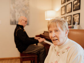 A resident listens as a man plays the piano at ComfortCare Homes.