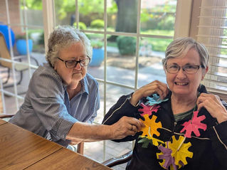ComfortCare Homes residents display a necklace made during activities.