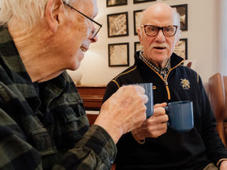 A resident and guest sharing cups of coffee.