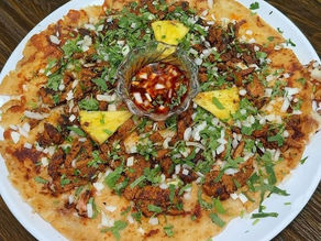 Al Pastor Pupusa Pizza topped with marinated pork, onions, cilantro, pineapple, and house salsa served at Pupusería Las Cabañas.