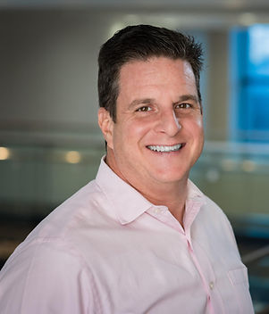 Blonde woman smiling wearing a blue jacket and a white shirt