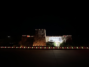Commercial building outlined with warm white Christmas lights during evening hours