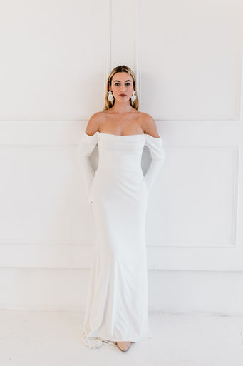 A crepe fitted wedding dress with long, off-the-shoulder sleeves.