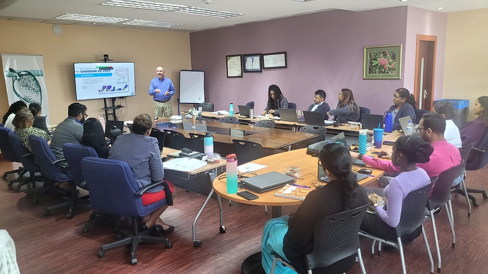 A person presents to a group in a conference room, using a screen displaying "GAUSSIAN VS. PUFF." Attendees are seated with laptops.