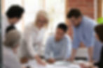 Serious old mature woman team leader coach teach young workers explain paper business plan