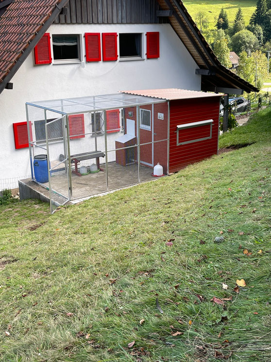 Hühnerstall mit Auslaufgehege an einem Wohnhaus.