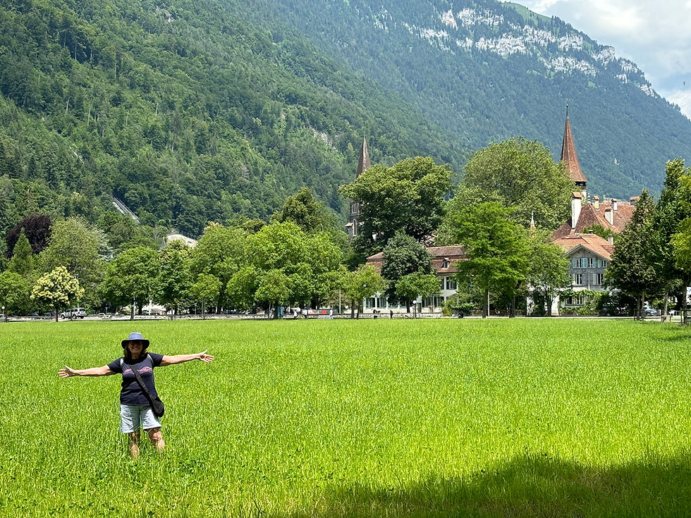 Karen stood arms outstretched in a field of long grass in Interlaken