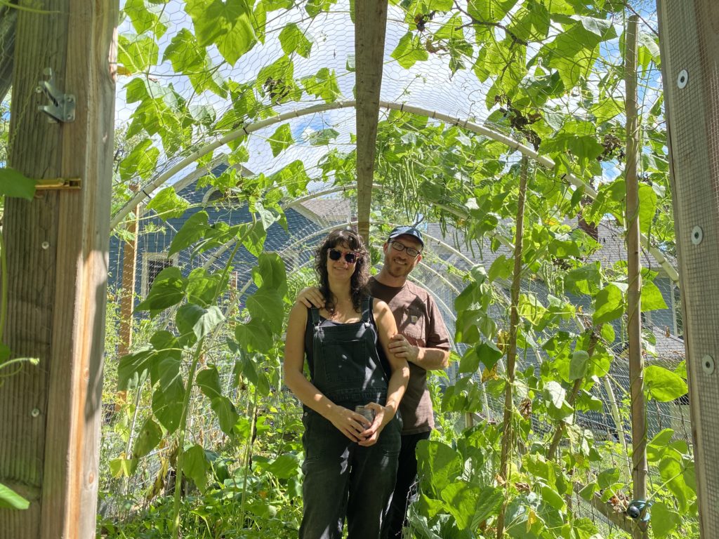 Annabel and Dylan pose under their home-made hoop house, full of sunflowers.