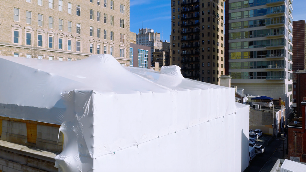 Shrink wrap containment installed over the scaffold structure to protect the exposed building exterior.