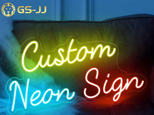 Neon text reading "Custom Neon Sign" in yellow, blue, and red on a dark sofa background. GS-JJ logo in the top left corner. Bright and vibrant.