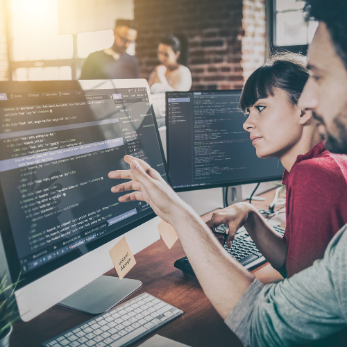 Statistical programmers collaborate in a modern office, analyzing data and refining code to ensure precision and accuracy in their work.