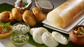 Dosa, idli, vada with chutneys and sambar served on a banana leaf