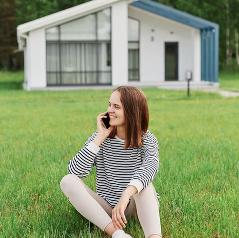 woman on phone in front of beautiful lawn