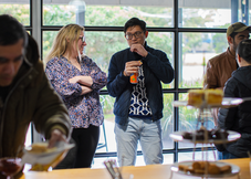 Casual networking event with professionals chatting and enjoying refreshments in a modern coworking space.