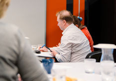Business professional taking notes during a workshop or training session in a modern conference room.