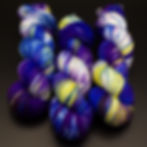 Skeins of hand dyed Doctor Who inspired yarn in a purple, blue and yellow colourway 