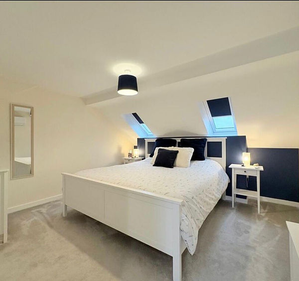 Modern bedroom with white bed and navy accents by WJO Stays