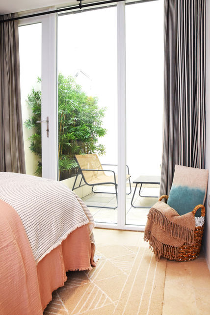 Bedroom with an armchair, balcony view, and a cozy, relaxing atmosphere.