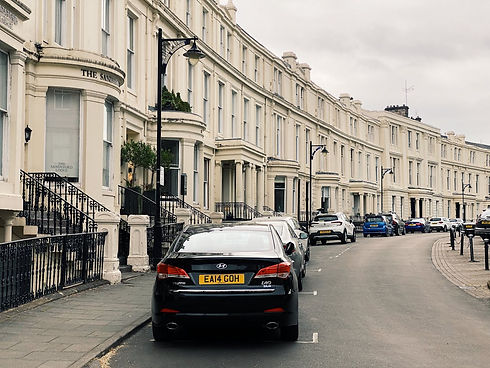 Row of parked cars along a street in front of buildings Hostroo