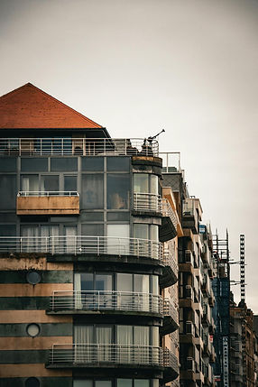 Modern apartment building with a red roof against cloudy sky Hostroo