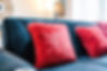Comfortable blue sofa with red pillows in a well-lit living room