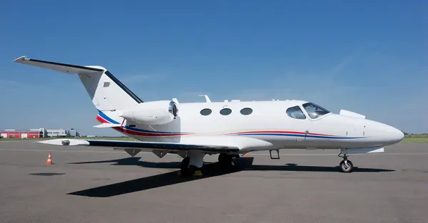 photo of a Citation Mustang a very light jet which can seat up to 4 passengers located on the ramp of a private airport in the summer