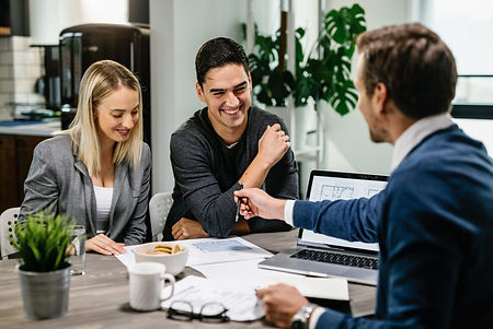 happy-couple-having-meeting-with-real-estate-agent-analyzing-blueprints-while-communicatin