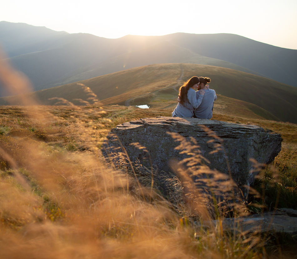 Couple sitting on a mountain rock at sunset