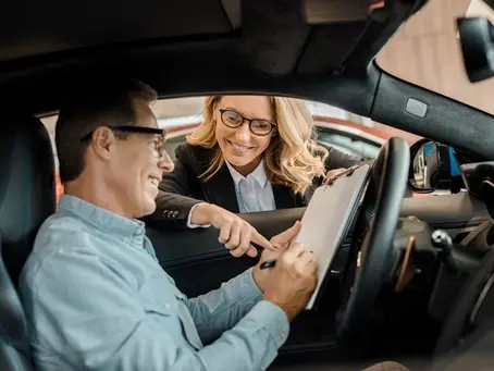 Associado assinando adesão da proteção veicular de dentro do carro e a consultora o instruindo pela janela