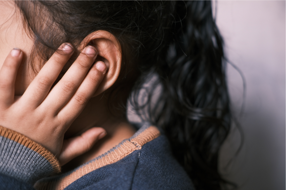 Girl holding her hand over one ear.