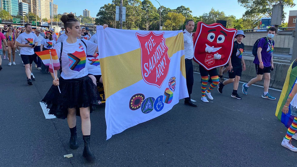 The Salvation Army group march behind the banner – being held by Salvos supporter Zoe Simpson and Captain Kris Halliday – which displays the Red Shield and five inclusion icons.