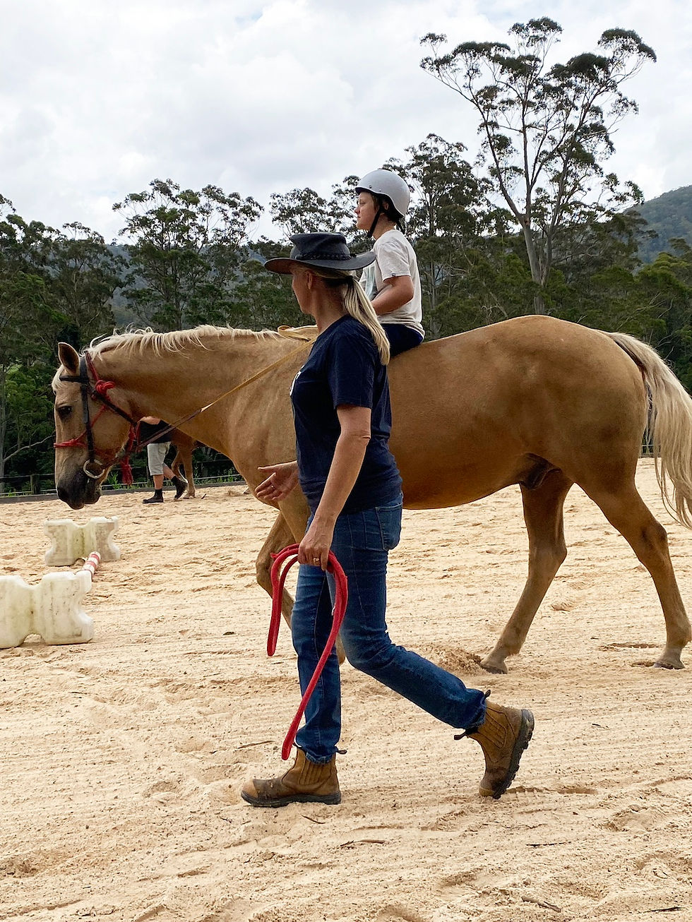 Danni guides a young person on a horse in her role as an equine therapy coordinator.