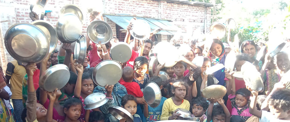 A large crowd of children and adults hold metal plates and bowls up in the air