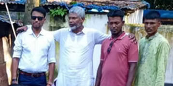 Four male volunteers stand together outdoors at a community relief distribution site in Bangladesh.