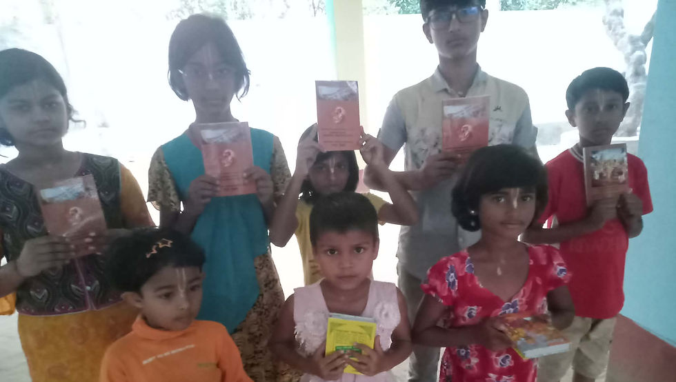 "A group of children stand together indoors, holding up small booklets and books they've received."