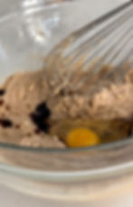 Cookie dough in a glass bowl with a whisk.