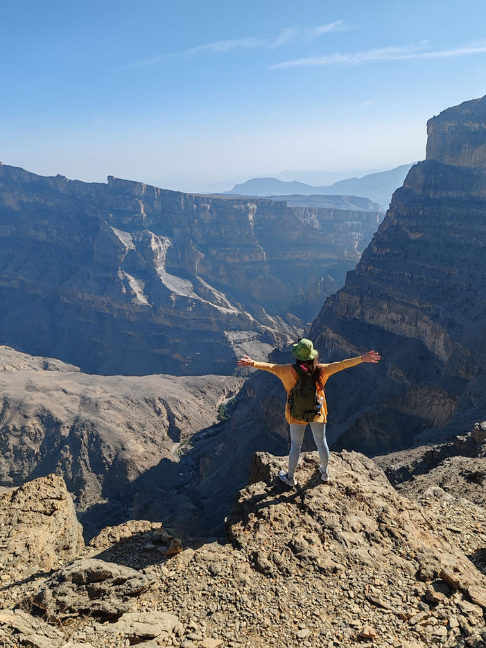 Hikers walking Jabal Shams Balcony Walk Oman with panoramic canyon views and mountain trail.