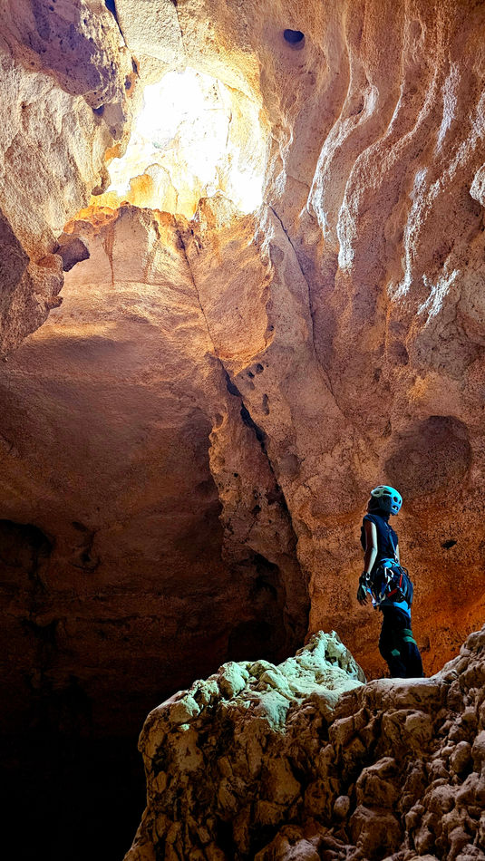 Caver standing inside the giant chamber of the 7th Hole during a 120m drop caving adventure in Oman