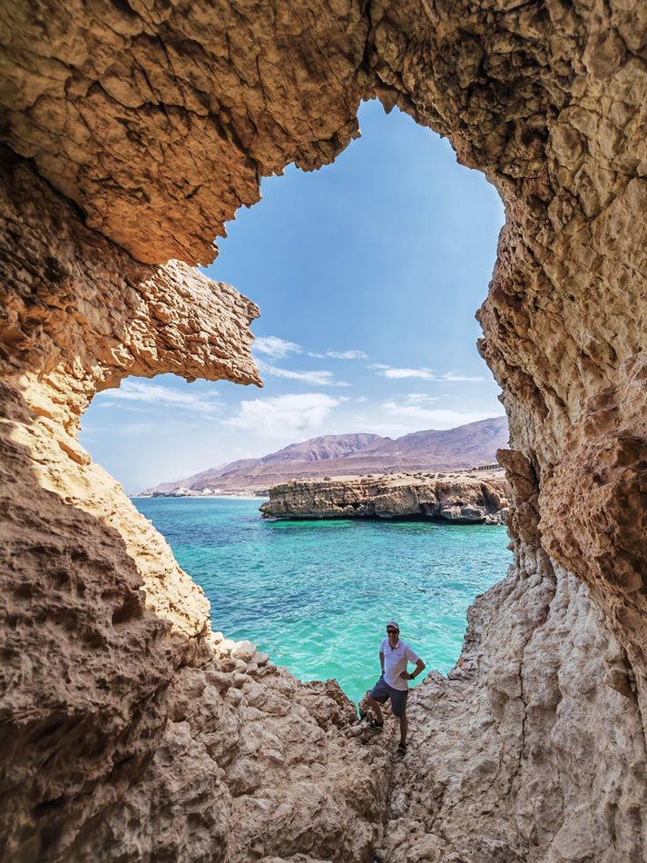 Natural cave opening framing the turquoise sea during a Wadi Shab and coastal tour in Oman