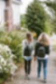 Two girls walking wearing backpacks