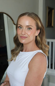 a bride after getting hair and makeup done at her bridal preview. her hair is done in soft waves and a middle part with hair tucked behind both ears