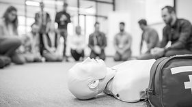 Kursteilnehmer in einem Erste-Hilfe-Kurs üben mit einer Puppe