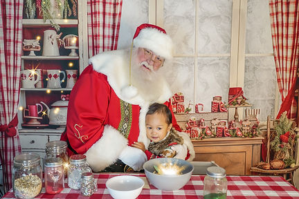 Santa and child hug while standing at the counter of a festive Christmas kitchen