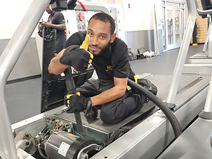 Reimagine Resources certified technician giving a thumbs up as he is repairing a treadmill
