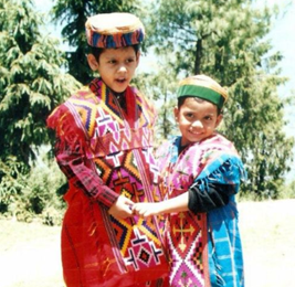 Two young brothers in formal Indian garb. One boy in vibrant red and a smaller boy, Gopul, in blue.