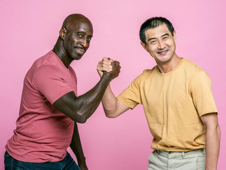 Two friends joyfully shaking hands against a lively pink background