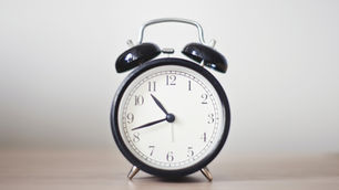an alarm clock on a wood desk representing time management