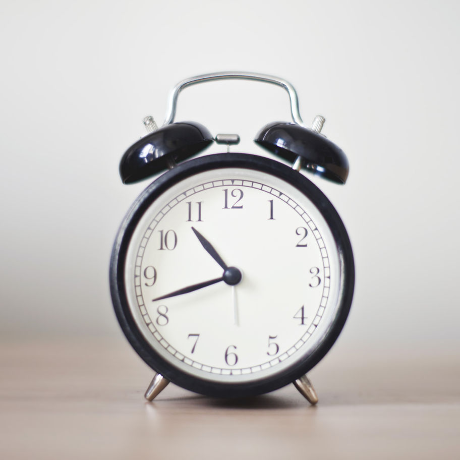 A picture of a black and white alarm clock on a wooden table.