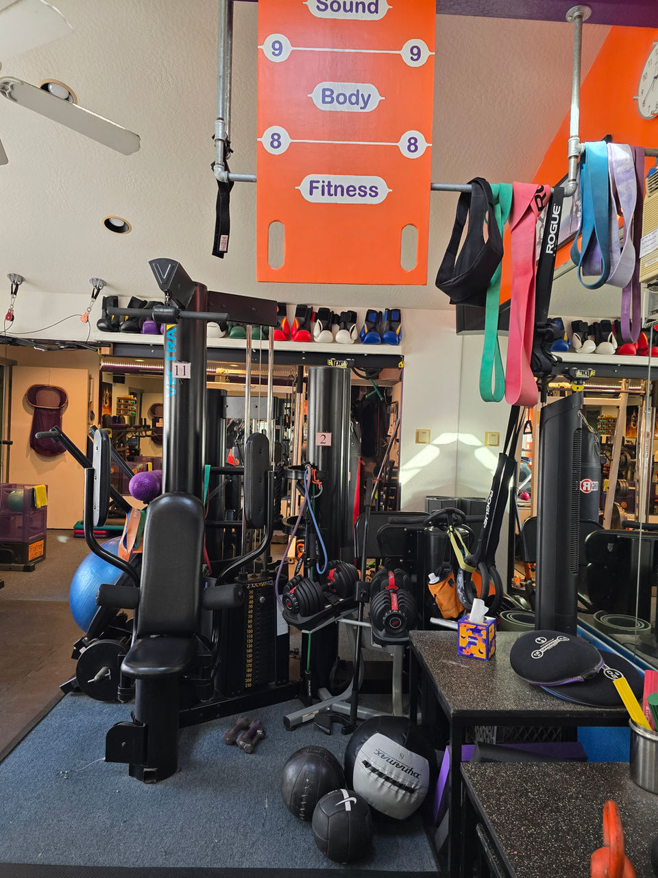 A workout area in the gym featuring resistance machines and colorful exercise balls for various training activities.
